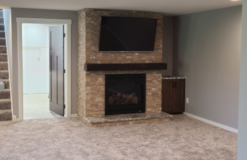 Finished basement with stone fireplace, television, and carpet flooring