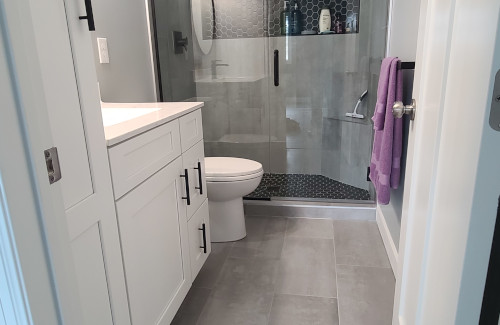 Remodeled bathroom with white vanity and glass walk-in shower