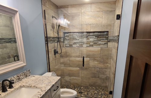 Remodeled bathroom with tiled walk-in shower and granite vanity