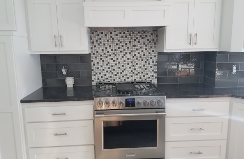 Kitchen remodel with white cabinets, stainless steel range, and tile backsplash