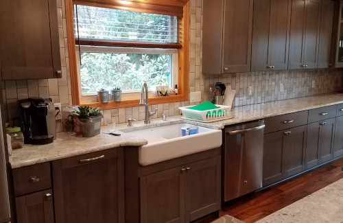 Remodeled kitchen with dark wood cabinets, farmhouse sink, and stone countertops